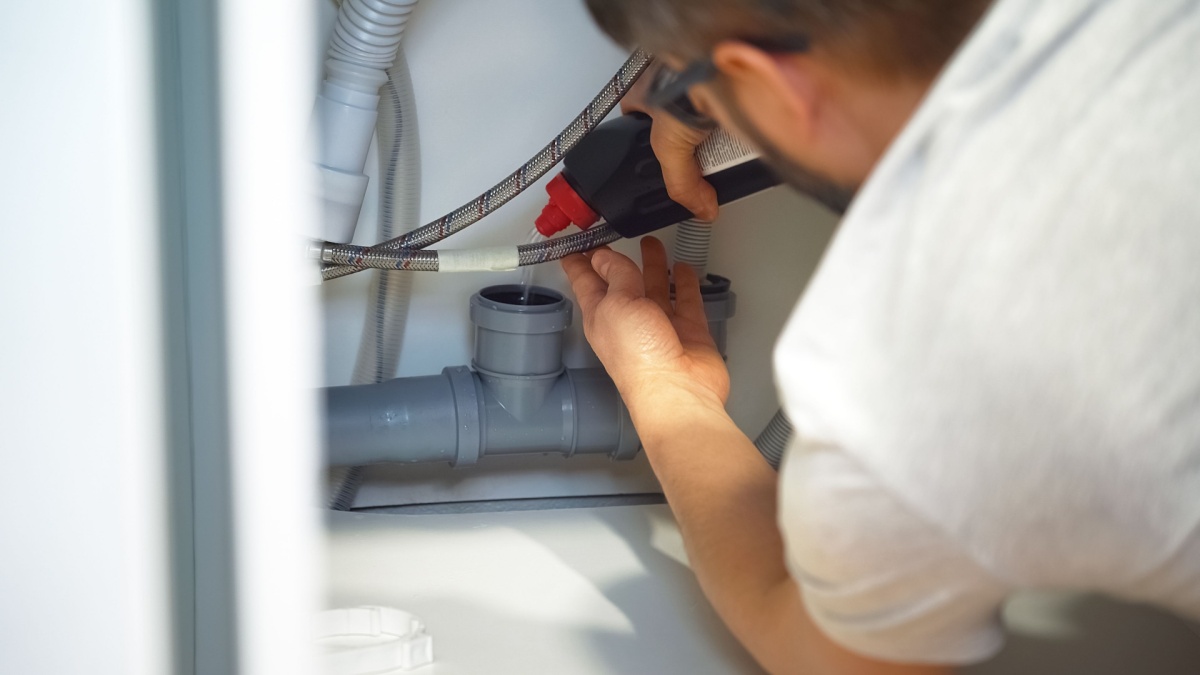 plumber using drain cleaner to clear a clogged pipe