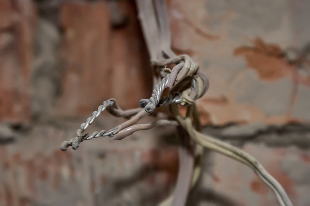 old electrical wiring sticking out from a brick wall in the basement of an older home