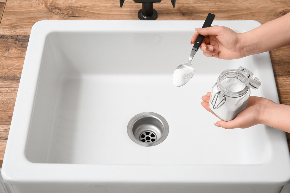 woman cleaning sink drain with baking soda